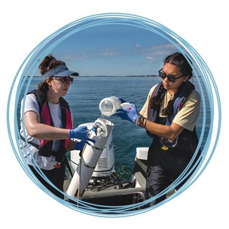 Two marine science students filling a sampling container with ocean water